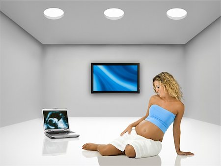 Beautiful pregnant woman seated on the floor inside a room with a laptop and tv Stock Photo - Budget Royalty-Free & Subscription, Code: 400-04176342