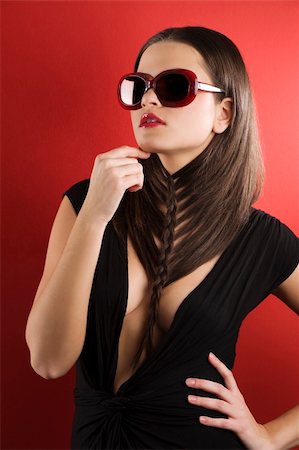 simsearch:400-05678958,k - young brunette on red background wearing sunglasses and black dress with a creative hair stylish Photographie de stock - Aubaine LD & Abonnement, Code: 400-04176530