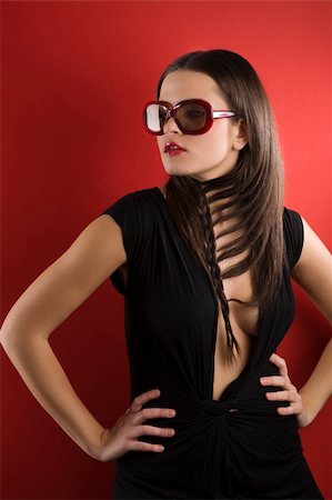 simsearch:400-05678958,k - young brunette on red background wearing sunglasses and black dress with a creative hair stylish Photographie de stock - Aubaine LD & Abonnement, Code: 400-04176532