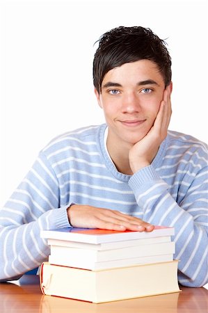 simsearch:400-04505681,k - Young student is sitting on desk with his books and smiles happy into camera. Isolated on white. Stock Photo - Budget Royalty-Free & Subscription, Code: 400-04179016