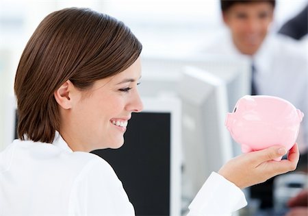 simsearch:400-04184165,k - Smiling businesswoman holding a piggybank in the office Stock Photo - Budget Royalty-Free & Subscription, Code: 400-04187010