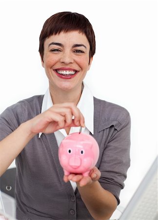 simsearch:400-04184165,k - Smiling businesswoman saving money in a piggybank in the office Stock Photo - Budget Royalty-Free & Subscription, Code: 400-04188060