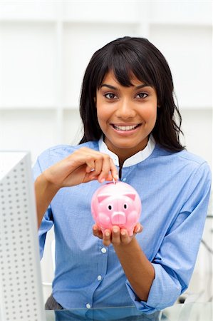 simsearch:400-04184165,k - Smiling businesswoman saving money in a piggybank in the office Stock Photo - Budget Royalty-Free & Subscription, Code: 400-04188097