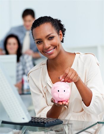 simsearch:400-04184165,k - Smiling businesswoman saving money in a piggy-bank at her desk Stock Photo - Budget Royalty-Free & Subscription, Code: 400-04188463
