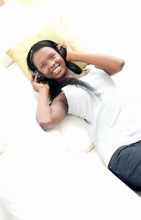 simsearch:400-04206778,k - Cheerful woman listening music with headphones lying on a sofa in the living-room Foto de stock - Super Valor sin royalties y Suscripción, Código: 400-04182965