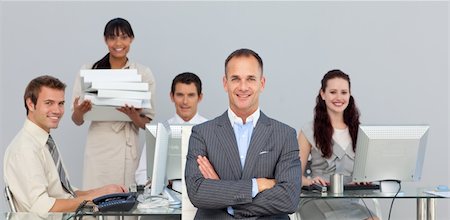 simsearch:400-04113367,k - Self-assured manager with folded arms with his team in the background Stock Photo - Budget Royalty-Free & Subscription, Code: 400-04183945