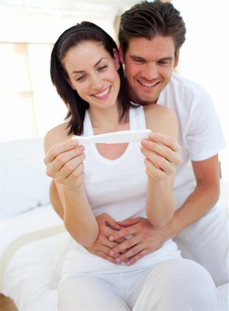Smiling couple finding out results of a pregnancy test sitting on  bed Stock Photo - Budget Royalty-Free & Subscription, Code: 400-04195564