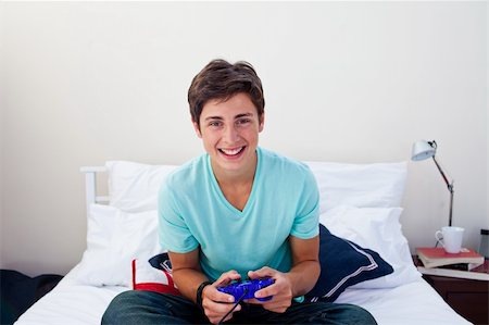 simsearch:400-05751526,k - Attractive happy teenager playing video games in his bedroom Stock Photo - Budget Royalty-Free & Subscription, Code: 400-04199106