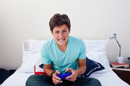 simsearch:400-05751526,k - Excited teenager playing video games in his bedroom Stock Photo - Budget Royalty-Free & Subscription, Code: 400-04199116