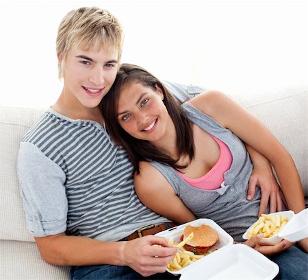simsearch:400-04199223,k - Teen couple eating burgers and fries on the sofa at home Stock Photo - Budget Royalty-Free & Subscription, Code: 400-04199151