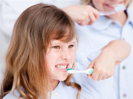 simsearch:400-04151137,k - Smiling girl brushing her teeth against a white background Photographie de stock - Aubaine LD & Abonnement, Code: 400-04190092