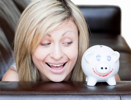 simsearch:400-04184165,k - Happy woman using a piggybank against a white background Stock Photo - Budget Royalty-Free & Subscription, Code: 400-04190838