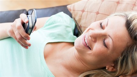 simsearch:400-04212823,k - Smiling woman using a phone in the living-room Stock Photo - Budget Royalty-Free & Subscription, Code: 400-04190978