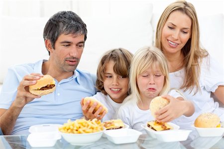 simsearch:400-04193348,k - Merry family eating hamburgers sitting on sofa Stock Photo - Budget Royalty-Free & Subscription, Code: 400-04193253