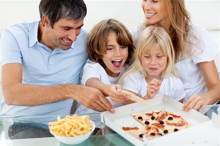 simsearch:400-04193348,k - Excited children eating a pizza with their parents in the living-room Stock Photo - Budget Royalty-Free & Subscription, Code: 400-04193288