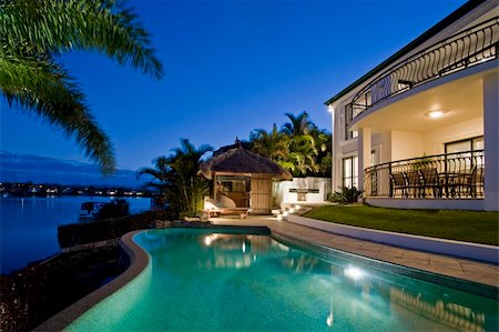 Luxurious mansion exterior at dusk overlooking pool, canal and Bali hut Stock Photo - Budget Royalty-Free & Subscription, Code: 400-04204353