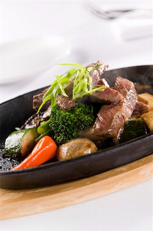 simsearch:400-07418409,k - Prime ribeye beef cooked to medium rare, served with an assorted mushroom mix of shitake, button and enoki, fresh vegetables and sauce, presented smoking and sizzling at your table Stock Photo - Budget Royalty-Free & Subscription, Code: 400-04204712