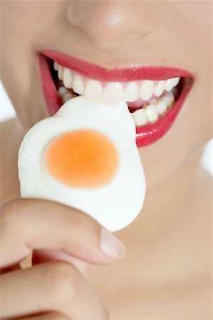 simsearch:400-04932642,k - Beautiful woman mouth with red lips eating a jelly egg Photographie de stock - Aubaine LD & Abonnement, Code: 400-04205460