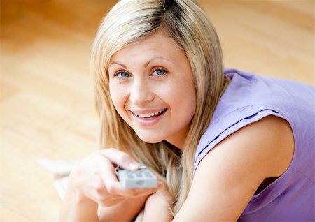 simsearch:400-04210845,k - Glowing blond woman watching TV holding a remot lying on the floor Stock Photo - Budget Royalty-Free & Subscription, Code: 400-04208031