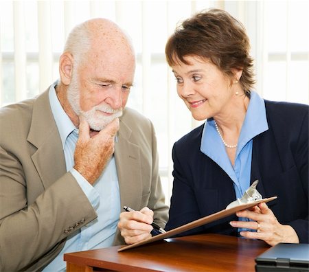 Senior man reading and thinking about a contract while eager businesswoman encourages him to sign. Stock Photo - Budget Royalty-Free & Subscription, Code: 400-04208632