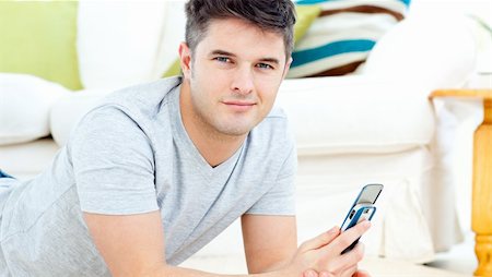 simsearch:400-04212823,k - Handsome man smiling at the camera sending a text lying on the floor at home Stock Photo - Budget Royalty-Free & Subscription, Code: 400-04209844