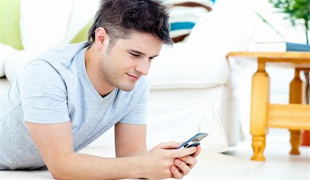 simsearch:400-04212823,k - Smiling man sending a text lying on the floor at home at home Stock Photo - Budget Royalty-Free & Subscription, Code: 400-04209845