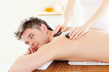 simsearch:400-04192063,k - Charming young man receiving a back massage with hot stone in a spa center Stock Photo - Budget Royalty-Free & Subscription, Code: 400-04209929