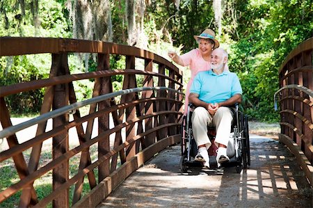 simsearch:400-04208630,k - Senior woman pushing her disabled husband through the park in his wheelchair. Stock Photo - Budget Royalty-Free & Subscription, Code: 400-04200049