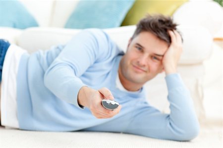 simsearch:400-04210845,k - Smiling young man holding a remote lying on the floor at home Stock Photo - Budget Royalty-Free & Subscription, Code: 400-04201893