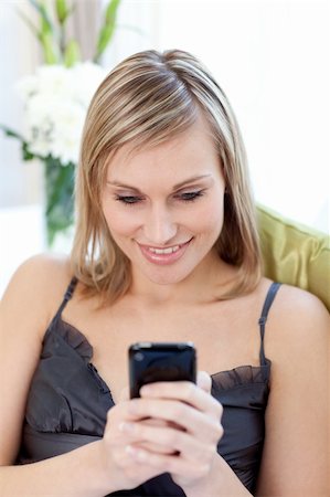simsearch:400-04212823,k - Beautiful woman sending a text sitting on a sofa at home Stock Photo - Budget Royalty-Free & Subscription, Code: 400-04202145