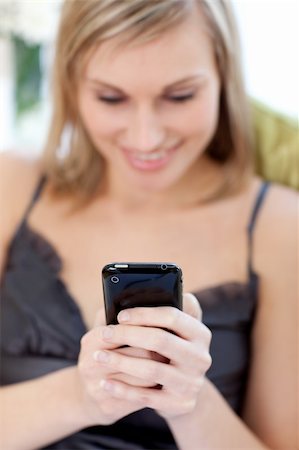 simsearch:400-04212823,k - Young woman sending a text sitting on a sofa at home Stock Photo - Budget Royalty-Free & Subscription, Code: 400-04202147
