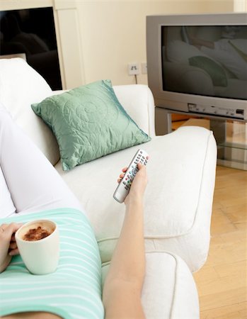 simsearch:400-04210845,k - Attractive woman drinking a coffee while watching TV lying on a sofa Stock Photo - Budget Royalty-Free & Subscription, Code: 400-04202267