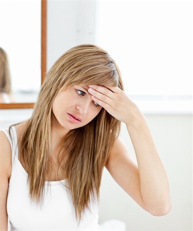 Depressed woman with a headache looking at the camera in the bathroom at home Stock Photo - Budget Royalty-Free & Subscription, Code: 400-04217631