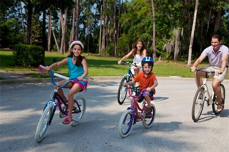 simsearch:400-05755734,k - A modern family of two parents and two children, a boy and a girl, cycling together. Photographie de stock - Aubaine LD & Abonnement, Code: 400-04219475