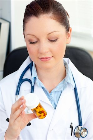 simsearch:6109-06005907,k - Serious young female doctor looking at pills sitting in her office Stock Photo - Budget Royalty-Free & Subscription, Code: 400-04210838