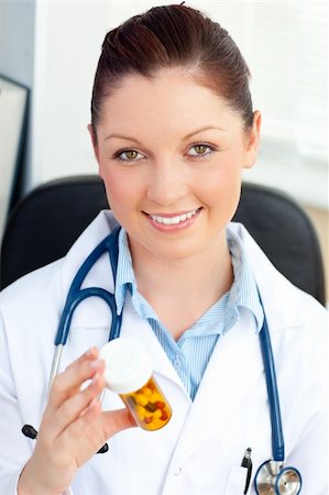 simsearch:400-05748252,k - Glowing young female doctor looking at pills sitting in her office Stock Photo - Budget Royalty-Free & Subscription, Code: 400-04210839