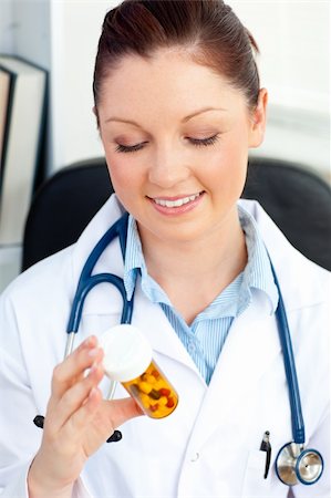 simsearch:400-05748252,k - Smiling female doctor holding pills sitting in her office in a hospital Stock Photo - Budget Royalty-Free & Subscription, Code: 400-04210850