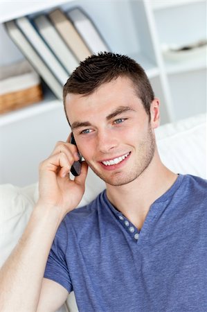 simsearch:400-04212823,k - Happy young man talking on phone sitting on a sofa at home Stock Photo - Budget Royalty-Free & Subscription, Code: 400-04212820