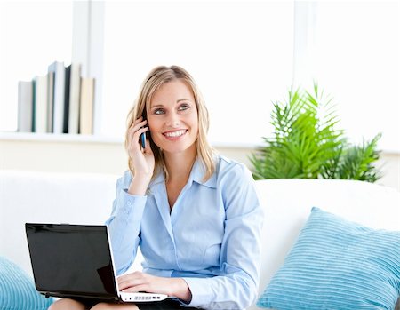 simsearch:400-04212823,k - Smiling businesswoman talking on phone and using her laptop sitting on a sofa at home Stock Photo - Budget Royalty-Free & Subscription, Code: 400-04212913