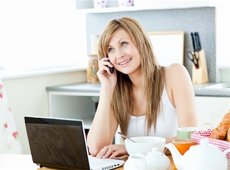 simsearch:400-04212823,k - Young caucasian woman using her laptop and talking on phone during breakfast in the kitchen at home Stock Photo - Budget Royalty-Free & Subscription, Code: 400-04213049