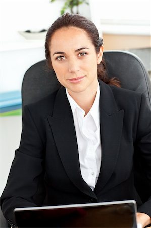 simsearch:400-05729275,k - Self-assured hispanic businesswoman sitting at her desk in front of her laptop in her office Stock Photo - Budget Royalty-Free & Subscription, Code: 400-04220838