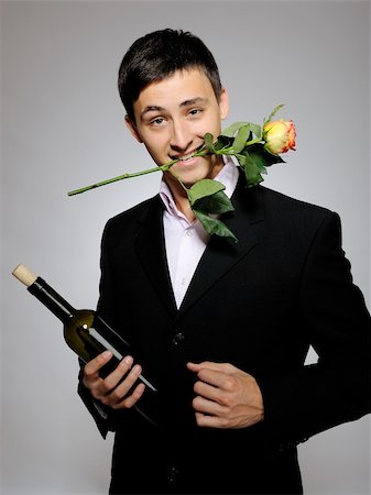 simsearch:400-04739802,k - Handsome romantic young man holding rose flower and vine bottle  prepared for a date. gray background Stock Photo - Budget Royalty-Free & Subscription, Code: 400-04235644