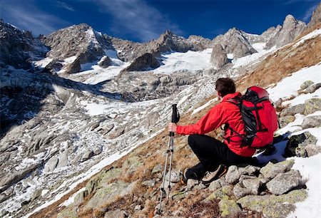 simsearch:400-04269017,k - Back view of a young male hiker while observing a high mountain panorama. Sitting position, red jacket, black pant. Triolet glacier, Mount Blanc massif, Italy, Europe. Photographie de stock - Aubaine LD & Abonnement, Code: 400-04237894