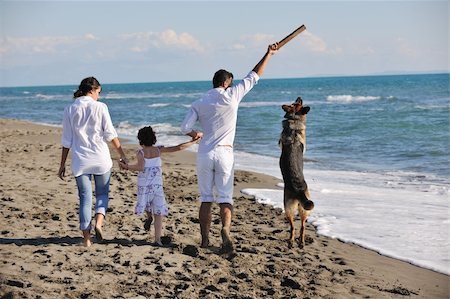 simsearch:400-05309800,k - happy young family in white clothing have fun and play with beautiful dog at vacations on beautiful beach Stock Photo - Budget Royalty-Free & Subscription, Code: 400-04239375