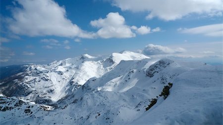 At the top of the highest ski lift of the Vogel ski resort in Bohinj. Clear blue sky with some clouds in the distance. Mountain range covered with snow in the centre. Stock Photo - Budget Royalty-Free & Subscription, Code: 400-04231325