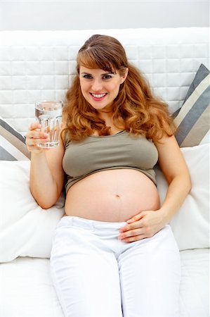 simsearch:400-04875116,k - Smiling pregnant woman relaxing on sofa at home with glass of water  in hand Stock Photo - Budget Royalty-Free & Subscription, Code: 400-04268444