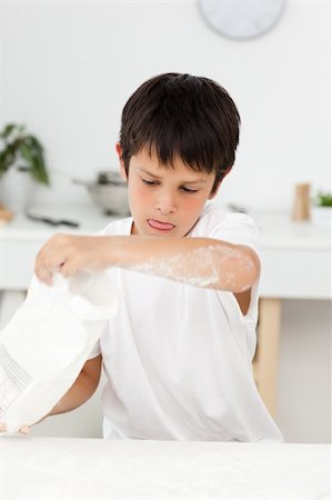 fun with flour - Cute boy pouring flour on a table in his kitchen at home Stock Photo - Budget Royalty-Free & Subscription, Code: 400-04268919