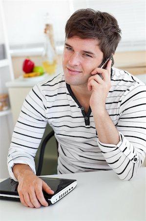 simsearch:400-04212823,k - Delighted man talking on phone using his laptop in the kitchen at home Stock Photo - Budget Royalty-Free & Subscription, Code: 400-04268975