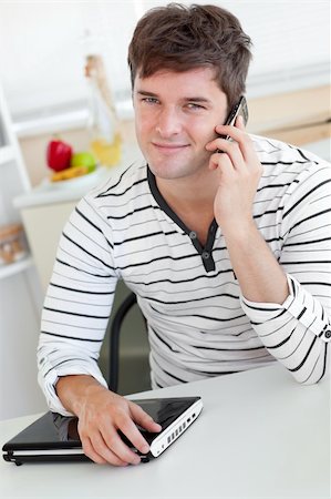 simsearch:400-04212823,k - Attractive man talking on phone using his laptop in the kitchen at home Stock Photo - Budget Royalty-Free & Subscription, Code: 400-04268976