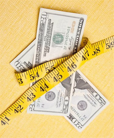 American currency is squeezed by a yellow measuring tape on a measuring background to demonstrate that money is tight. Stock Photo - Budget Royalty-Free & Subscription, Code: 400-04263691